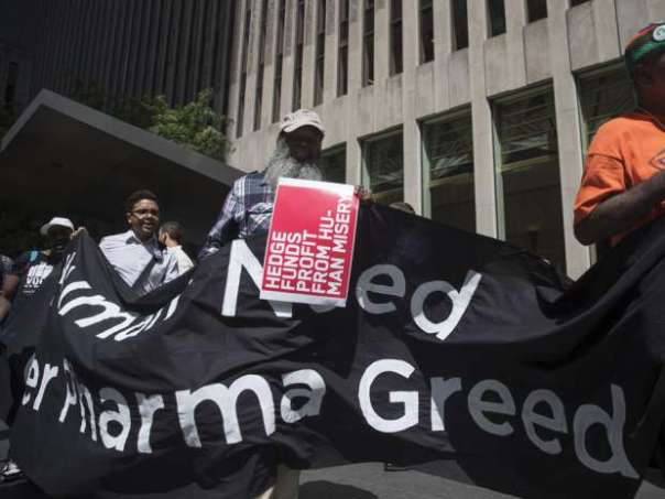 Demonstrators hold up signs during a protest outside the offices of John Paulson, founder of Paulson & Co., not pictured, for his hedge fund's investment in Mylan NV, in New York, U.S, on Tuesday, Aug. 30, 2016. Mylan NV has become the latest pharmaceutical company to provoke nationwide ire for steep price increases. Victor J. Blue/Bloomberg.